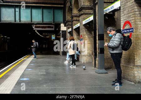Passagiere stehen auf dem Bahnsteig der Londoner U-Bahnstation Notting Hill Gate und warten auf einen Zug. Sie tragen Gesichtsmasken wegen des Coronavirus. Stockfoto