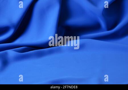 Der unscharfe, unscharfe Hintergrund besteht aus einem zarten blauen Chiffon-Stoff mit Falten in Form von Wellen. Selektiver Fokus. Stockfoto