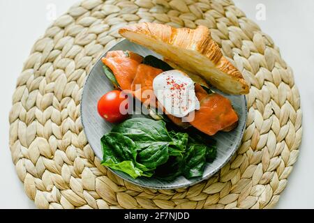 Croissant-Sandwich mit Quark, Lachs, Spinat und pochiertem Ei. Gesundes Frühstück. Draufsicht. Stockfoto