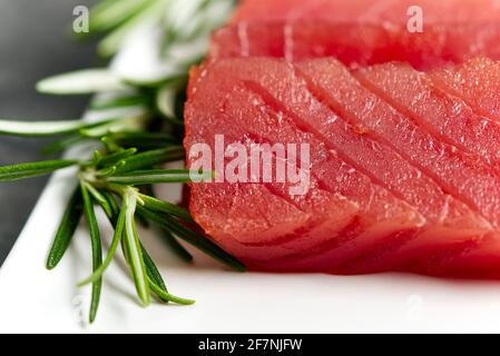 Rohe Thunfisch-Scheibe mit Rosmarin auf dem weißen Teller Stockfoto