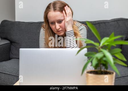 Junge Frau, die mit einem Laptop auf der Couch sitzt. Business, Arbeiten von zu Hause Konzept Stockfoto