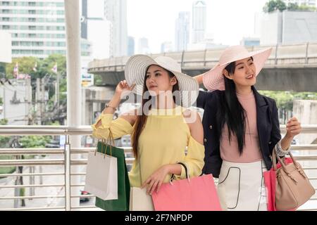 Junge asiatische Frau Freunde genießen mit halten bunte Einkaufstasche An der Fassade des Kaufhauses Stockfoto