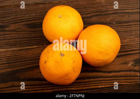 Drei frische, saftige Orangen auf einem Holztisch. Nahaufnahme mit selektivem Fokus. Stockfoto