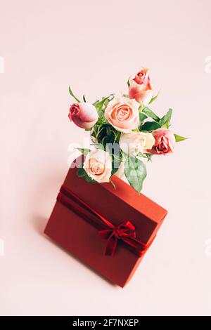 Schöne frische Rosen festliche Geschenkbox auf pastellrosa Hintergrund. Kopieren Sie die Raumvorlage für eine Postkarte. Vertikaler Rahmen Stockfoto