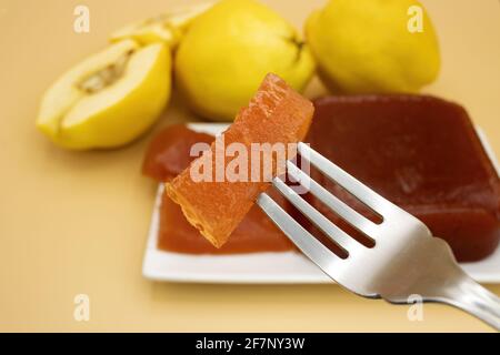 Selektiver Fokus auf eine köstliche hausgemachte Quitten-Marmelade, hausgemachtes Quitten-Fleisch, auf einem cremigen Hintergrund, mit Quitten außer Fokus im Hintergrund Stockfoto