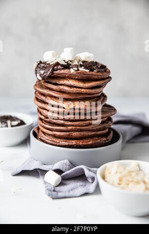 Schokoladen-Pfannkuchen mit geschmolzener Schokolade, gemahlener Mandel und Marschmalow, heller Hintergrund. Selektiver Fokus. Stockfoto