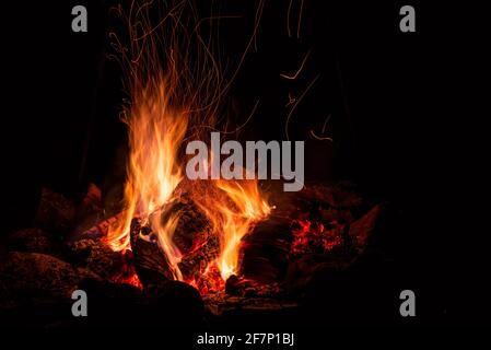 Nachtlager mit verfügbarem Platz. Großes Lagerfeuer vor schwarzem Hintergrund. Funken von Lagerfeuer und Feuer aus der Nähe Stockfoto