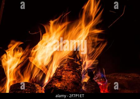 Nachtlager mit verfügbarem Platz. Großes Lagerfeuer vor schwarzem Hintergrund. Funken von Lagerfeuer und Feuer aus der Nähe Stockfoto