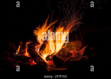 Nachtlager mit verfügbarem Platz. Großes Lagerfeuer vor schwarzem Hintergrund. Funken von Lagerfeuer und Feuer aus der Nähe Stockfoto