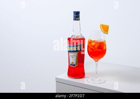 Lugansk, Ukraine - 29. März 2021: Aperol Spritz Cocktail. Aperol in Flasche und Weinglas mit Eis auf weißem Hintergrund. Langes kohlensäurehaltiges Getränk. Minimale Kre Stockfoto