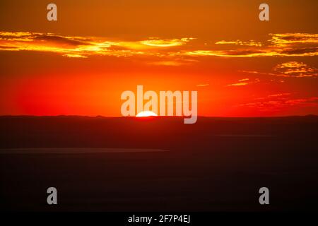 Untergehende Sonne über den Bergkämmen als Hintergrund; Steppenseen bei Dämmerung im Vordergrund Stockfoto