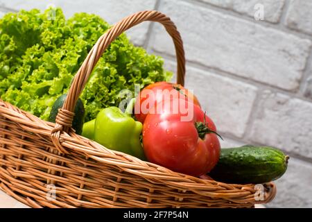 Frisches Gemüse mit Wassertropfen in den Korb gelegt. Bio-Tomaten, Gurken, Pfeffer und grüner Salat vom Markt. Frische Rohkost. Stockfoto