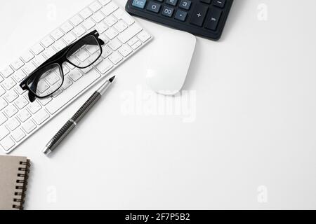 Büroarbeitsplatz mit Tastatur Maus Brille Stift und Rechner eingeschaltet Weißer Hintergrund Stockfoto