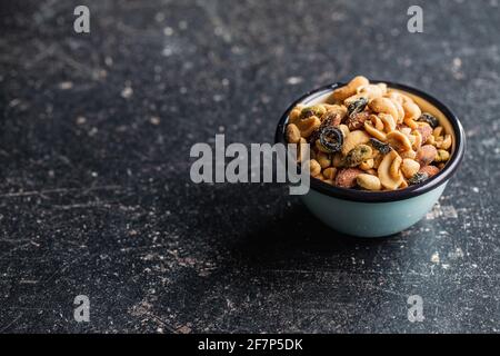 Gesalzene Nüsse in einer Schüssel auf einem schwarzen Tisch mischen. Stockfoto