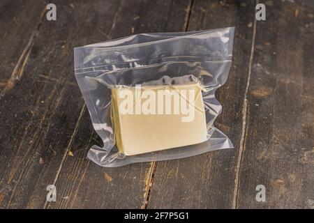 Frische Butter in einer Vakuumverpackung auf Holzhintergrund Stockfoto