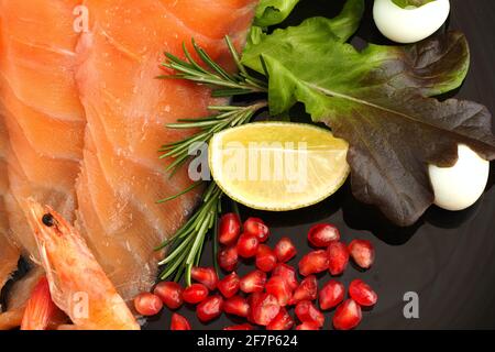 Roter Fisch. Scheiben gesalzener Lachs auf einem schönen Teller mit Zitronengranatapfel Rosmarin und Wachtelei. Stockfoto