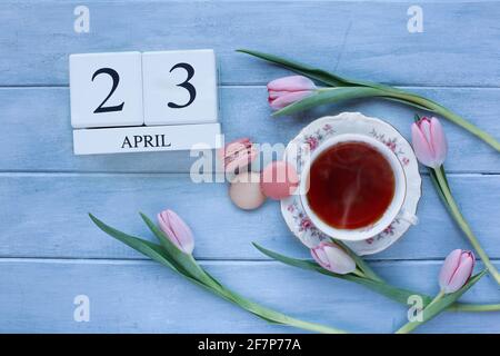 Ansicht Französisch rosa Erdbeere und Kaffee aromatisierte Macarons, heißen Tee und Holz Kalender Blöcke auf einem blauen rustikalen Tisch.. Stockfoto