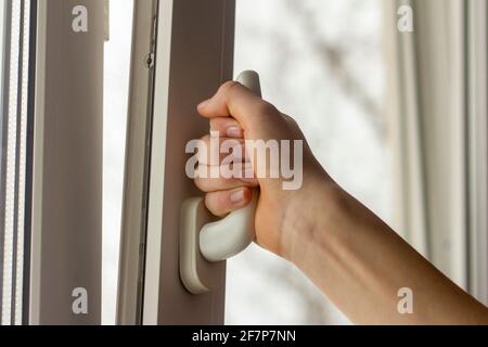 Die Hand des Teenagers öffnet das Fenster, um das auszulüften Zimmer Stockfoto