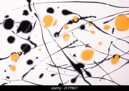 Schwarze und gelbe Linien und Spritzer auf weißem Hintergrund gezeichnet. Abstrakt getupfter Hintergrund mit orangefarbenem Pinselstrich. Acrylmalerei mit Grafik s Stockfoto