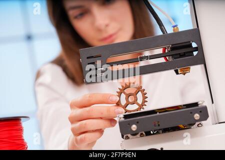 Junge Designerin, die an einem Prototyp-Gerät auf einem 3D-Drucker arbeitet Stockfoto