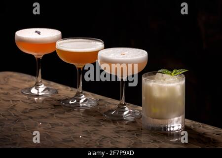 Nahaufnahme einer Cocktail-Auswahl aus vier direkt servierten und einem on the rocks Getränken, alle mit Eiweiß, fruchtig und kräftig Stockfoto