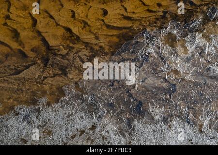 Frühling schöne Muster aus Eiskruste und gemustertem bräunlichen Boden In einem kleinen Bach Stockfoto
