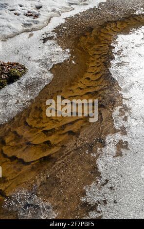 Gebogene Streams mit gemustertem Boden und eisigen Bänken während Die Feder tauen auf Stockfoto