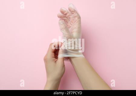 Weibliche Hände in Einweghandschuhen auf rosa Hintergrund Stockfoto