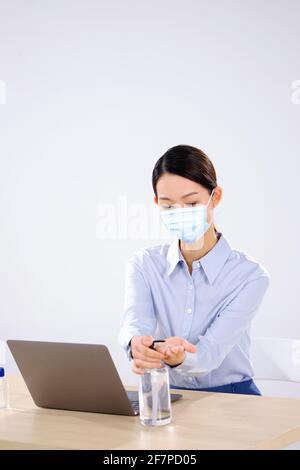 Eine Geschäftsfrau, die eine Maske trägt, verwendet die Seite des Händedesinfektionsmittels Anzeigen Stockfoto