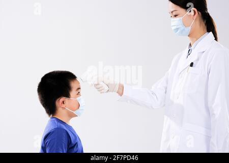 Eine Ärztin nahm die Temperatur des kleinen Jungen ins Gesicht Gesicht Stockfoto