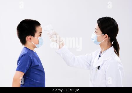 Eine Ärztin nahm die Temperatur des kleinen Jungen ins Gesicht Gesicht Stockfoto