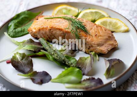 In der Pfanne gebratenes Lachsfilet mit Dill, Zitrone und etwas Salat Stockfoto