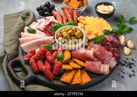 Nahaufnahme des Charcuterie-Boards. Fleischsnacks verschiedener Art, Käse und Oliven auf dunkelgrauem Hintergrund. Stockfoto