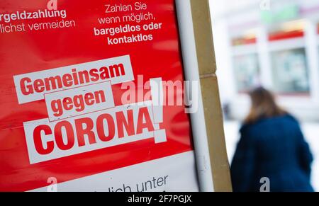 Hof, Deutschland. April 2021. Eine Frau kommt an einem Plakat vorbei, auf dem „Zusammen gegen Corona“ im Stadtzentrum steht. Die Stadt Hof hat weiterhin die höchsten Corona-Infektionszahlen in ganz Deutschland. Quelle: Nicolas Armer/dpa/Alamy Live News Stockfoto