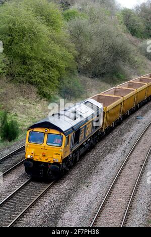 Die Diesellokomotive GBRf der Baureihe 66 Nr. 66748 'West Burton 50' zieht leere Network Rail Lastwagen in Hatton Bank, Warwickshire, Großbritannien Stockfoto