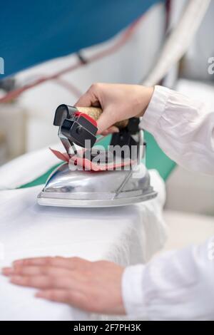 Womans Hände mit Eisen über helle Kleidung Stockfoto