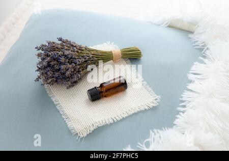 Mit ätherischem Lavendelöl für besseren Schlaf. Aromatherapie-Konzept. Lavendelöl und Bouquet von getrockneten Lavendelblüten auf Kissen. Stockfoto