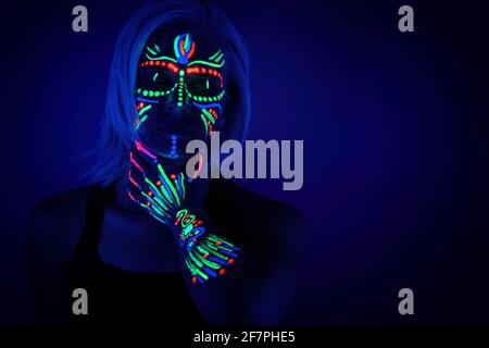 Porträt einer Frau mit Neon-Make-up, die von fluoreszierender Farbe in ultraviolettem Licht gemacht. Stockfoto