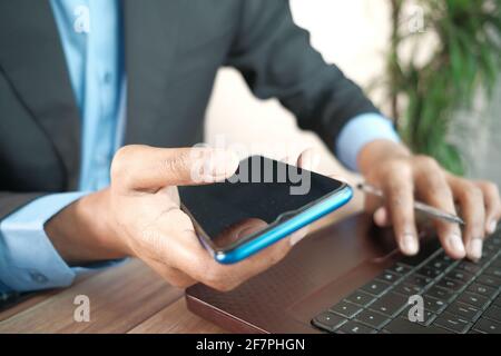 Geschäftsmann Hand mit Smartphone und tippen auf Laptop Stockfoto