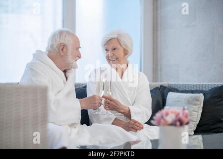 Seniorenpaar in weißen Roben feiert und schaut glücklich aus Stockfoto