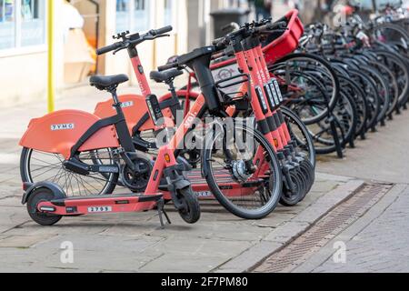 VOI-Elektrofahrräder und -Roller, die bei einer Sammlung geparkt sind Point for hire in Cambridge UK Stockfoto