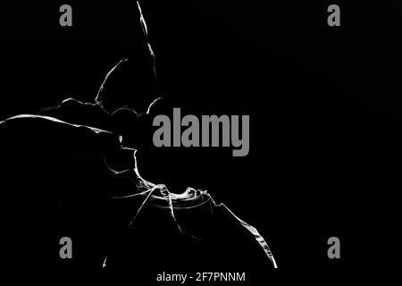 Risse im Glas, Löcher von Kugeln auf schwarzem Hintergrund. Stockfoto