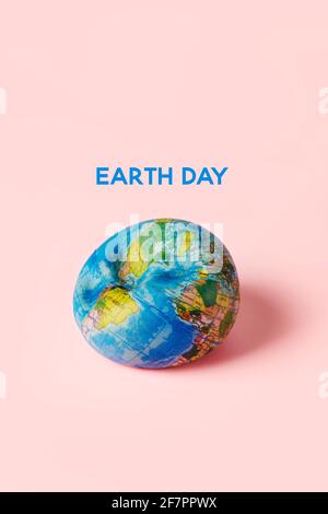 Ein verformter weicher Erdglobus und der Text Earth day Auf einem rosa Hintergrund Stockfoto