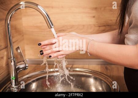 Nicht erkennbare Frau, die sich die Hände wascht und die Seife abspült Stockfoto