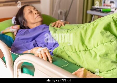 Ältere Patienten Hand mit Injektion Kochsalzlösung im Krankenhausbett liegend. Stockfoto