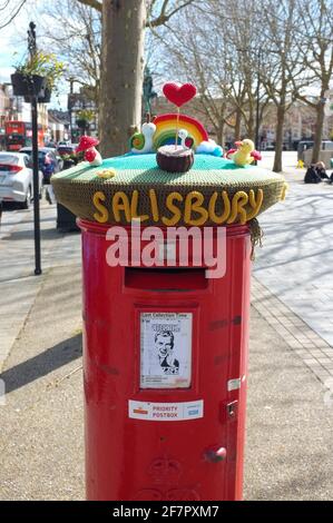 Ein roter Briefkasten mit Strickmütze, der dem NHS in der Nähe des Markts von Salisbury in Wiltshire gewidmet ist. April 2021. Stockfoto