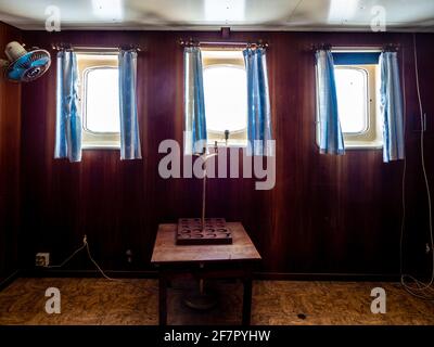 Drei Fenster mit blauen Vorhängen an einer roten Wand Stockfoto