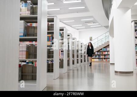 (210409) -- SHANGHAI, 9. April 2021 (Xinhua) -- Risalet Ehmet spaziert in der Bibliothek in Shanghai Lixin University of Accounting and Finance in Shanghai, Ostchina, 7. April 2021. Risalet Ehmet, 19, stammt aus dem Bezirk Zepu in Kashgar, nordwestlich der Autonomen Region Xinjiang Uygur in China. Heute studiert sie an der School of Information Management der Shanghai Lixin University of Accounting and Finance. Mit Hilfe von Lehrern und Mitschülern passte sie sich schnell an das Universitätsleben an. „nach dem Studium werde ich das Gelernte nutzen, um die Spezialitäten aus meiner Heimatstadt via zu bewerben Stockfoto