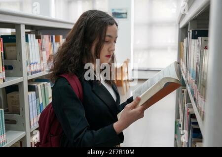 (210409) -- SHANGHAI, 9. April 2021 (Xinhua) -- Risalet Ehmet wählt Buch in der Bibliothek in Shanghai Lixin University of Accounting and Finance in Shanghai, East China, 7. April 2021. Risalet Ehmet, 19, stammt aus dem Bezirk Zepu in Kashgar, nordwestlich der Autonomen Region Xinjiang Uygur in China. Heute studiert sie an der School of Information Management der Shanghai Lixin University of Accounting and Finance. Mit Hilfe von Lehrern und Mitschülern passte sie sich schnell an das Universitätsleben an. „nach dem Studium werde ich das Gelernte einsetzen, um die Spezialitäten aus meinem Zuhause zu bewerben Stockfoto