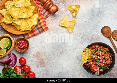 Traditionelle mexikanische Tomatensauce Salsa mit Nachos und Zutaten Tomaten, chile, Knoblauch, Zwiebel auf hellem Schieferstein Hintergrund. Konzept des lateinischen am Stockfoto